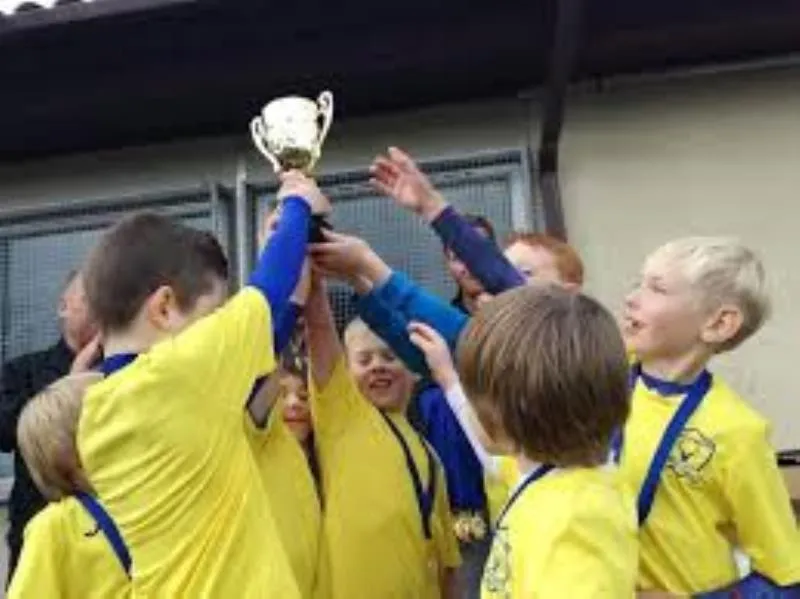 Bootle Bucks players in yellow shirts lifting a trophy together